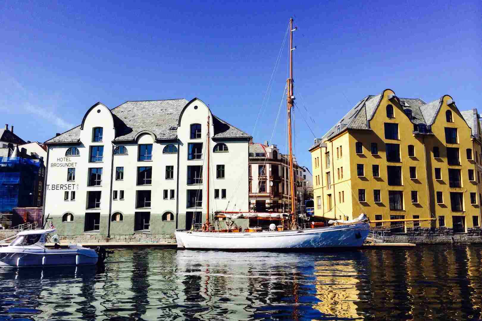 Hotel Brosundet in Alesund with two nice boats in front of it, one powered by an engine and the other powered by the wind