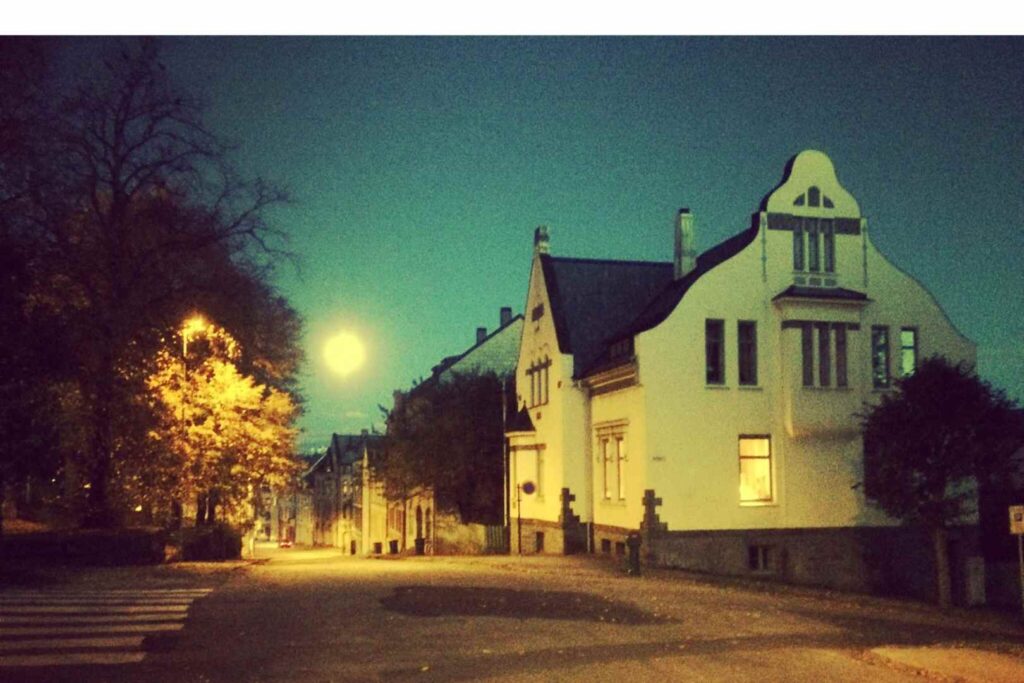 It has become night in the city of Alesund and a light illuminates a very dark street where a beautiful art nouveau building can be seen, one of the most beautiful in Norway