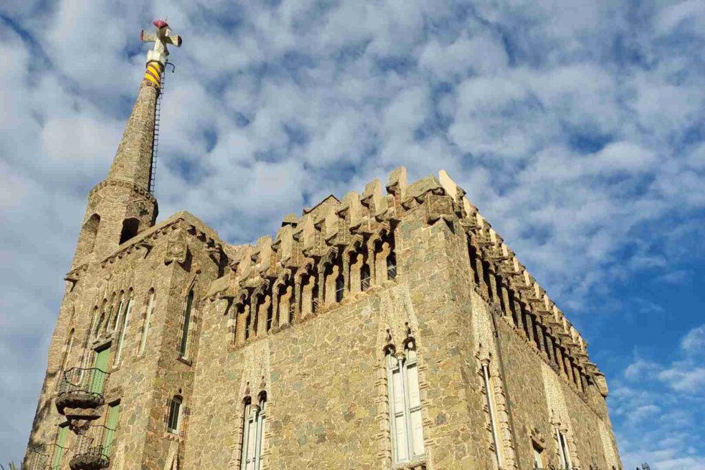 Bellesguard is a building that resembles a castle. It has a beautiful towr with a cross on top, Barcelona